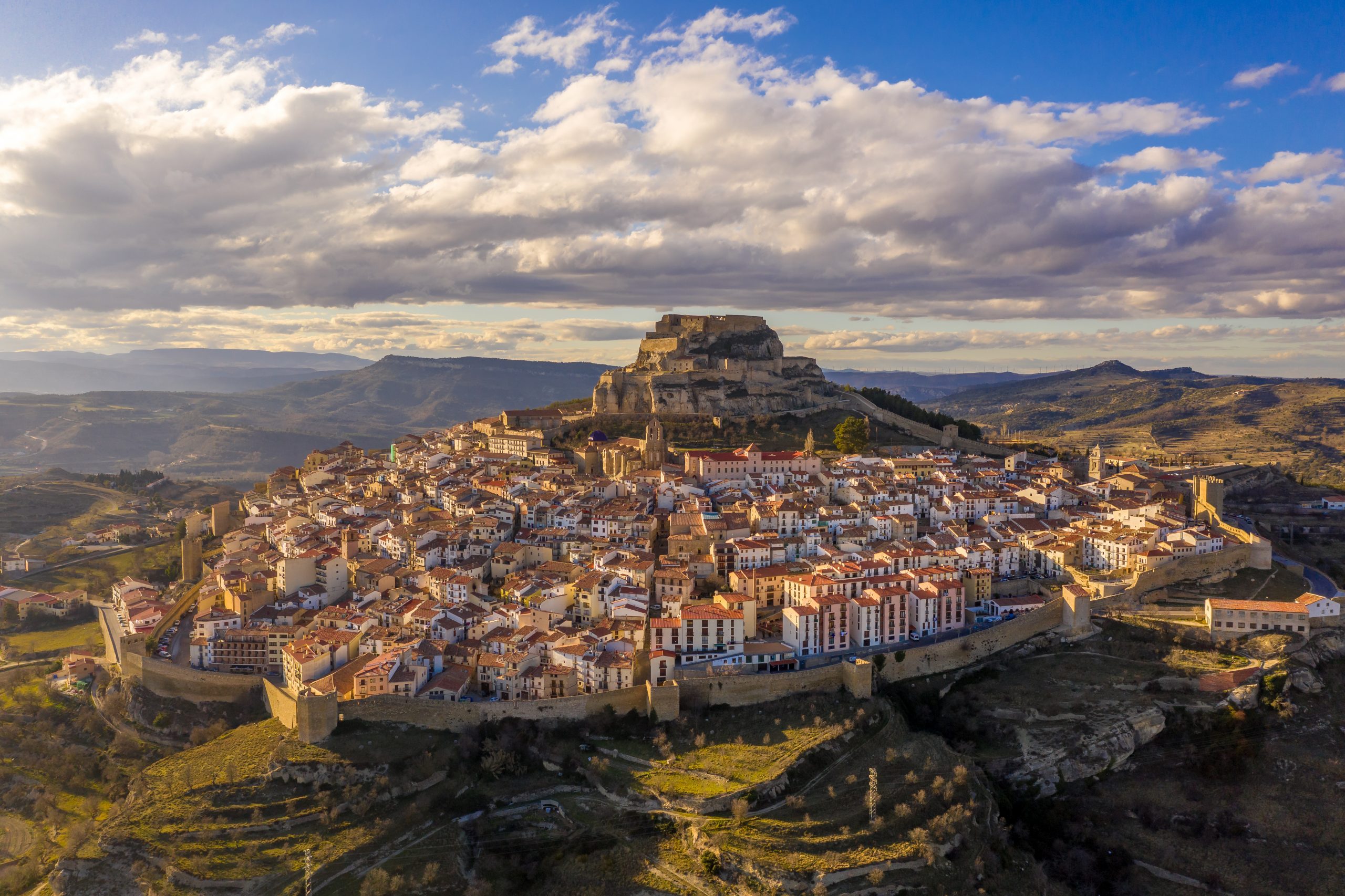 Aerial winter afternoon view of walled medieval Morella with cre